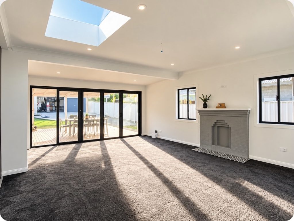 Newcastle renovation – living room with stacker doors, skylight and painted brick fireplace