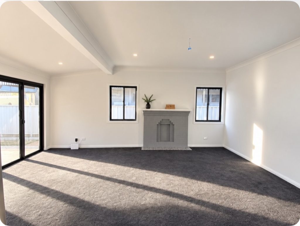 Newcastle renovation – living room with feature fireplace and black-framed windows